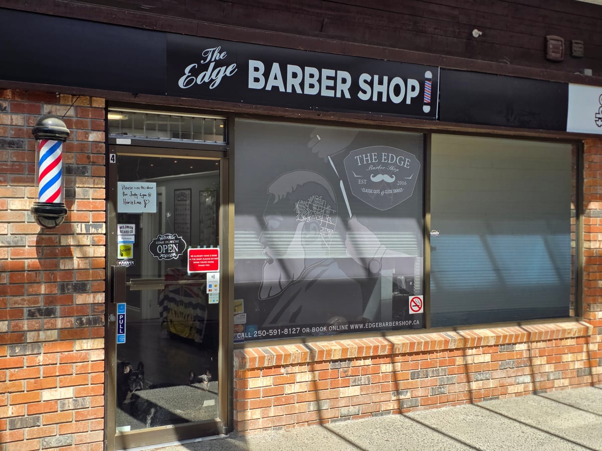 The Edge Barber Shop's storefront in Beban Plaza: the sign over the door, a barber pole and the shop's window decal
